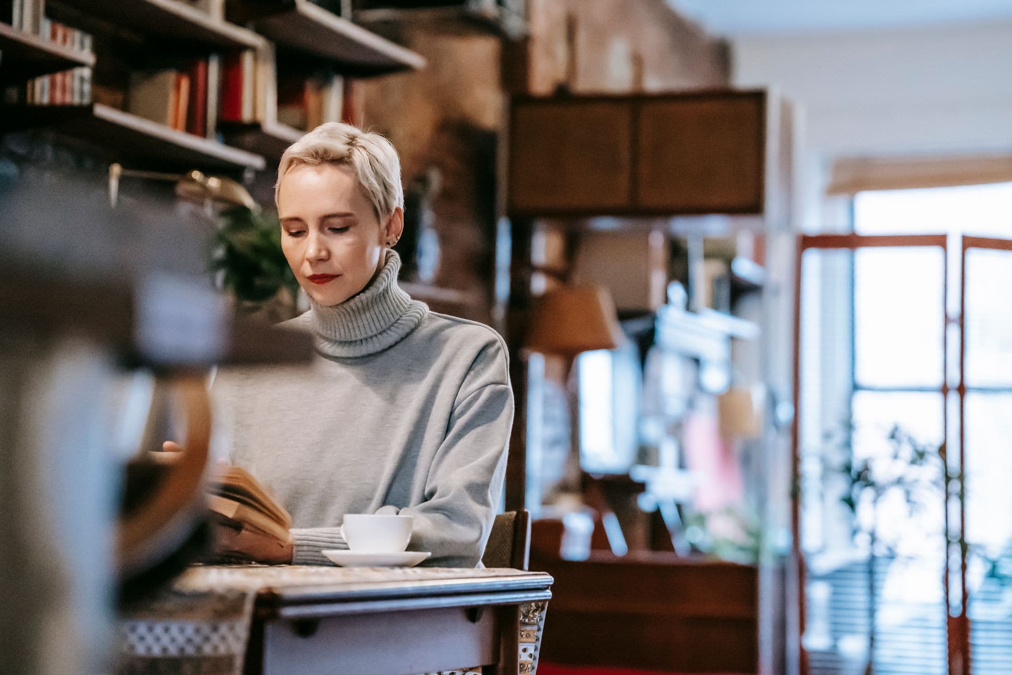 Mulher lendo em um ambiente acolhedor, com uma xícara de café